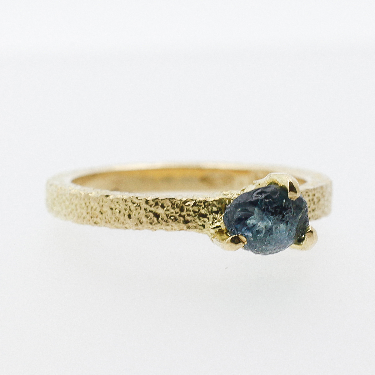 Yellow gold engagement ring with a rough sapphire in a solitaire.